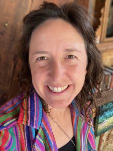 Kali Quinn, smiling at the camera in a colorful striped shirt